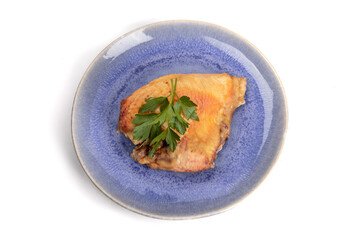 Wall Mural - A baked skin on chicken breast with garnish on a blue plate isolated on white