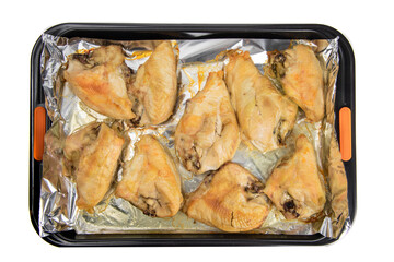 Wall Mural - Top down view of a foil lined tray of oven baked skin on chicken breasts isolated on white