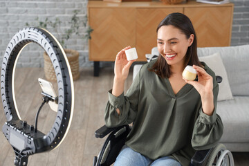 Poster - Female blogger in wheelchair with jars of cream recording video at home