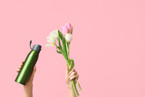 Fototapeta Panele - Female hands with sports bottle of water and bouquet of tulip flowers for International Women's Day on pink background
