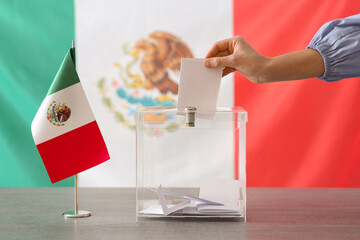 Voting woman with Mexican flag near ballot box on table at polling station