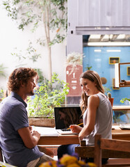 Wall Mural - Students, talking and smiling in coffee shop with laptop and notes for studying and break. Young people, friends and cheerful together with tech, internet and email for research or tutor at cafe