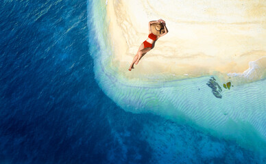 Wall Mural - Aerial view of beautiful young woman in red swimsuit lying on sandy beach near blue sea with waves at sunset Summer vacation at Andaman Island	