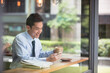 © Image Smith - Asian Businessman reading his smart phone in a cafe.