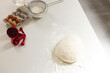 A mound of flour with dough sits on a kitchen counter with copy space, surrounded by baking ingredie
