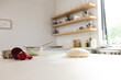 A kitchen counter is dusted with flour, featuring dough and a red measuring cup with copy space