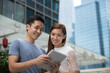 © Image Smith - Asian man and woman using digital tablet outdoors.