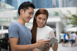 © Image Smith - Asian man and woman using digital tablet outdoors.