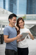 © Image Smith - Asian man and woman using digital tablet outdoors.