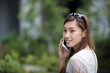 © Image Smith - Asian woman using her mobile phone in the street.