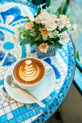 Hot coffee latte with latte art milk foam in cup mug on marble floor desk As breakfast In a coffee shop at the cafe, during business work concept