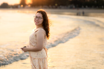 Asian woman in summer dress walks on a tropical beach the beach at Chao Samran Beach Phetchaburi Thailand, summer holiday trip Holiday travel concept.