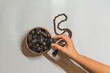 Fototapeta  - A wooden bowl with dried dates, a wooden rosary and a date in a woman's hand. Ramadan Kareem holiday concept