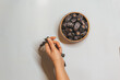 Wooden rosary in a woman's hand and dried dates in a wooden bowl. Ramadan kareem background