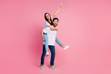 Wall Mural - Full length photo of lovely young couple hold piggyback raise hand have fun wear trendy white outfit isolated on pink color background