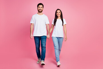 Wall Mural - Full length photo of lovely young couple hold hands walking dating wear trendy white outfit isolated on pink color background