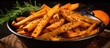A bowl of homemade french fries seasoned with orange sweet potato salt and pepper, topped with a fresh sprig of rosemary.