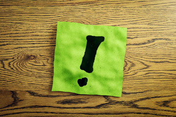 Poster - Close up of green note paper with exclamation mark on wooden desk. Questions and answers concept. 3D Rendering.