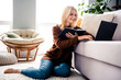 © deagreez - Photo of adorable lovely retired woman sitting on floor carpet writing notes chatting online video call meeting indoors