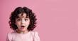 An amazed girl with curly dark hair in pink background