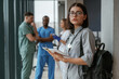 © standret - Beautiful woman in glasses is standing. Group of doctors are together indoors