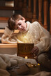 Boy kid sitting with with a fabulous box and gifts near to the stairs in Christmas. New Year, happiness and fairy tale