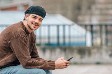 Sticker - portrait of young man with mobile phone outdoors on the street wearing urban style cap