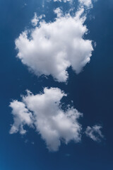 Two white fluffy clouds in blue sky natural background