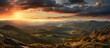 The painting depicts a vibrant sunset over the Czech Republics Orlicke hory mountain range. The sky is ablaze with hues of orange, pink, and purple, casting a warm glow over the rugged peaks.