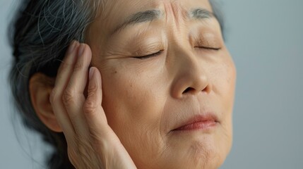 Wall Mural - A close-up of an elderly person with closed eyes resting their head on their hand conveying a sense of contemplation or tiredness.