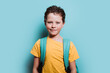 © ADDICTIVE STOCK - A happy young boy with a backpack smiles against a turquoise background, exuding confidence and excitement for school