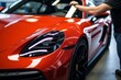 © Yuliia - Professional unrecognizable Caucasian specialist male man guy worker master wrapping installing protective film vinyl foil new red sport car automobile transport paint protection indoors salon service