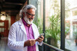 © ADDICTIVE STOCK - Mature doctor smiling while using smartphone in hospital. Generative AI image