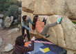 © ADDICTIVE STOCK - Focused climbers work in unison on a boulder problem outdoors, with a spotter ensuring their safety