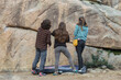 © ADDICTIVE STOCK - Back view of three climbers stand before a large boulder, contemplating the best route to tackle their next climb