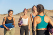 © ADDICTIVE STOCK - Joyful friends preparing for yoga on the beach at sunset