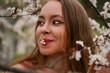 © Anna Ivanovska - flowers in mouth, beautiful blond natural hair woman in pink outfit is posing in botanical garden park near blooming tree with flowers. Spring and purity, natural beauty