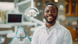 Handsome smiling African american dentist doctor stands in a dental office in a white coat