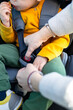 Hands of caucasian woman is fastening security belt to child, who is sitting in safety car chair