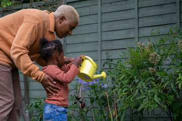 Wall Mural - Mother and daughter (2-3) watering plants in garden