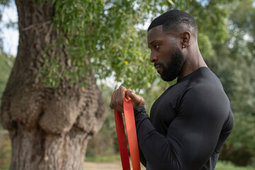 Wall Mural - Athletic man exercising with resistance band in park