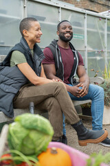 Wall Mural - Smiling couple relaxing on bench in front of greenhouse