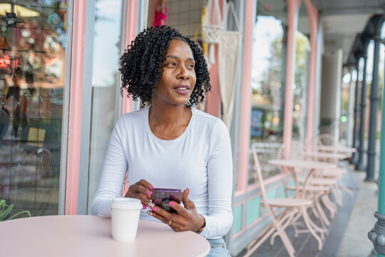 Woman using smart phone during coffee break in sidewalk cafe