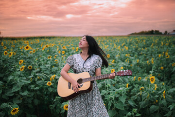 Wall Mural - Woman playing guitar in sunflower field