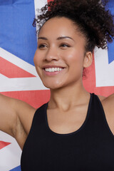 Wall Mural - Studio portrait of smiling athletic woman holding British flag