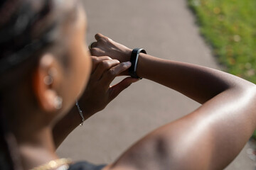 Wall Mural - Young woman checking watch after jogging