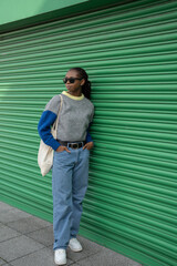 Wall Mural - Young stylish woman standing in front of green door