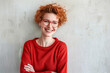 Joyful Redhead Woman in Stylish Glasses and Vibrant Sweater Radiating Positivity Against Textured White Background