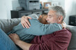 © Cultura Creative - Smiling male couple hugging on sofa at home