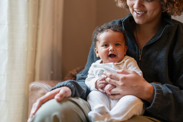 Canvas Print - Young mother holding baby girl on lap at home